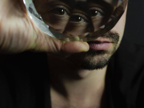 Person holding a faceted glass in front of their face with only neck and chest visible.