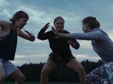Drei junge Frauen in sportlicher Kleidung in einer kämpferischen Pose im Freien vor bewölktem Himmel