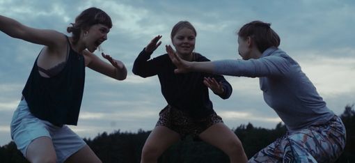 Drei junge Frauen in sportlicher Kleidung in einer kämpferischen Pose im Freien vor bewölktem Himmel