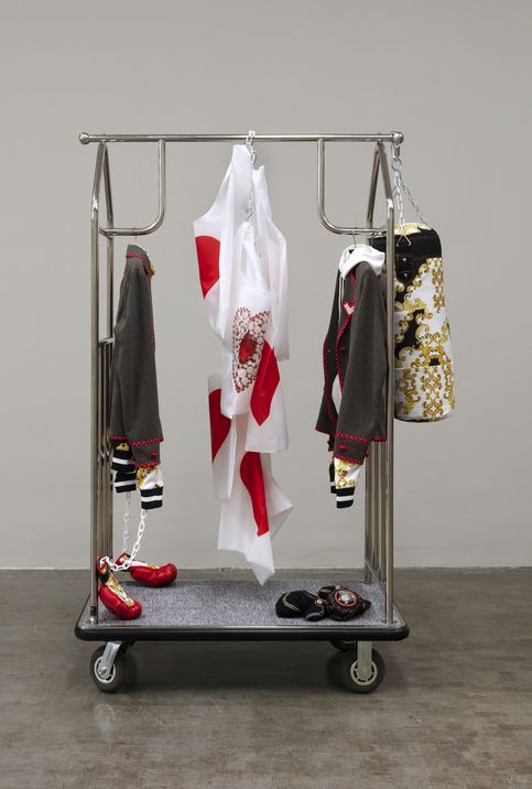 A sculpture by Chalisée Naamani made of different textiles presented on a luggage trolley.