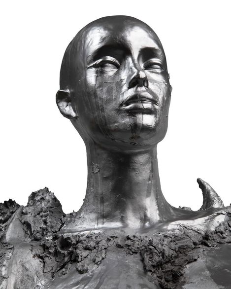 Black-and-white sculpture of a head and neck with rough, uneven texture and pointed protrusions at the base of the neck.