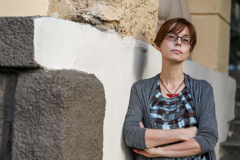 Person with crossed arms leaning against a wall made of rough stone and plaster.