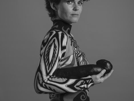 Person wearing a patterned sweater holding two elongated objects in their hands with face obscured.