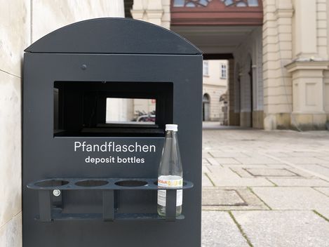 schwarzer Pfandbehälter an der Seite eines Mistkübels im MQ