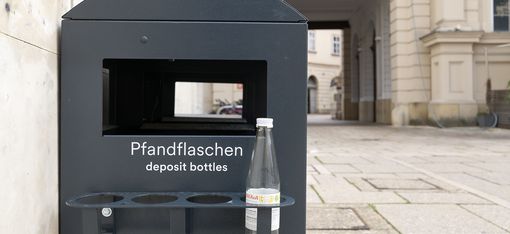 Black deposit container on the side of a trash can in the MQ