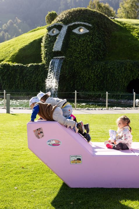 Kinder klettern und sitzen auf einem rosa Enzi vor dem Riesen der Swarovski Kristallwelten in Wattens.