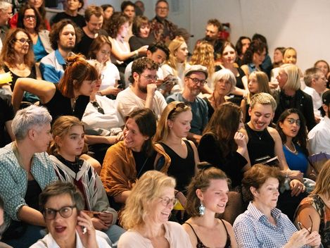 A large crowd is packed tightly onto the steps; some are laughing, chatting and looking ahead.