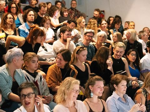 A large crowd is packed tightly onto the steps; some are laughing, chatting and looking ahead.