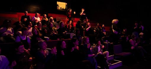 Viele Menschen sitzen dicht gedrängt im Zuschauerraum und haben Spaß.