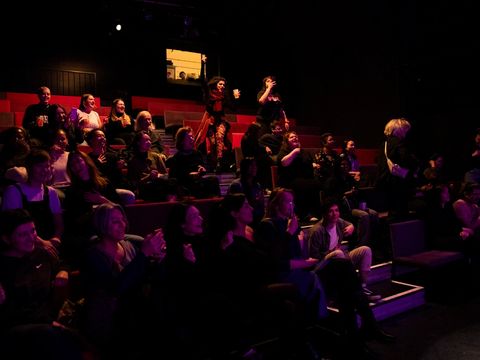 Viele Menschen sitzen dicht gedrängt im Zuschauerraum und haben Spaß.