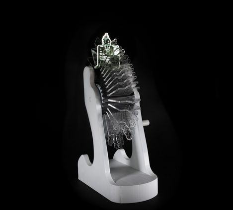 Sculpture with multiple transparent layered acrylic plates on a white base against a black background.