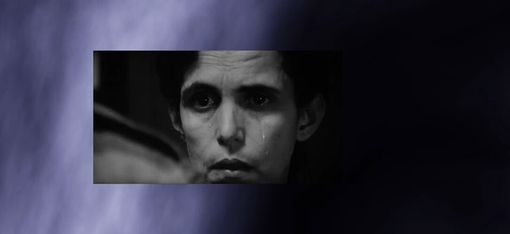 Crying person with dark hair on a blue-black background