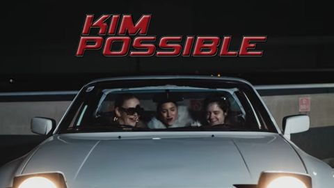 Drei Personen sitzen in einem weißen Sportwagen in einer dunklen Garage. Darüber steht in großer roter Schrift „KIM POSSIBLE“.