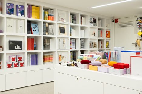 White shelving wall in the museum shop displaying art and design books, with selected design products in the foreground.