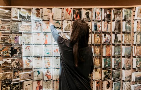 A person selects art postcards from a large wall display in the Leopold Museum shop.