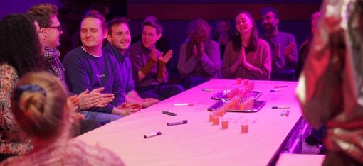 Several young people are sitting around a table, engrossed in conversation and discussion.