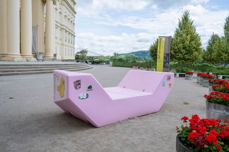 The pink Enzi stands in front of the Baroque façade of Klosterneuburg Abbey. Stickers from various cultural institutions are attached to the seating furniture, while red flowers add colourful accents around the square.