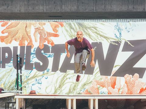 Mann in Bewegung springt vor einer Wand mit großem Schriftzug und Meeresmuster