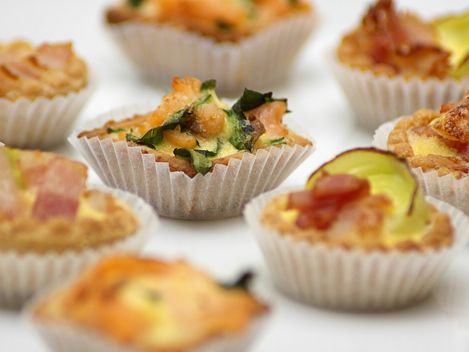 Eine Vielzahl von Mini-Muffins in verschiedenen Geschmacksrichtungen sind ordentlich auf einer weißen Fläche angeordnet.