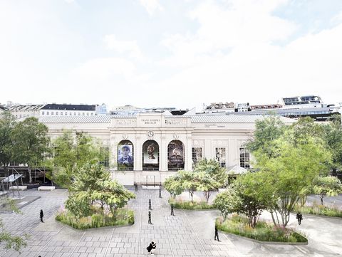 Visualisierung Staudeninseln im MQ Haupthof.
Das historische Gebäude des Tanzquartier mit seinen Bögen und Säulen bildet die Kulisse für den weitläufigen MQ Hauptplatz , der von Bäumen gesäumt ist und auf dem Menschen flanieren. Die Szene ist hell und ruhig.