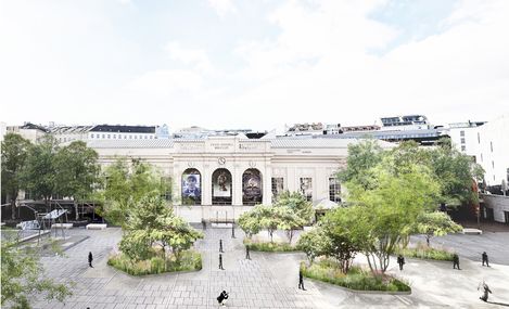 Visualisierung Staudeninseln im MQ Haupthof.
Das historische Gebäude des Tanzquartier mit seinen Bögen und Säulen bildet die Kulisse für den weitläufigen MQ Hauptplatz , der von Bäumen gesäumt ist und auf dem Menschen flanieren. Die Szene ist hell und ruhig.