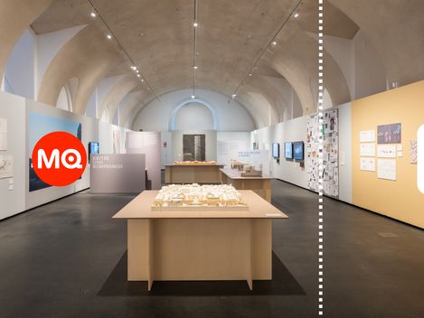 Interior view of the exhibition at MQ Freiraum featuring architectural models, documents, and multimedia displays.