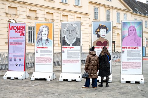 Fünf große Informationsstelen mit Porträtfotos und Texten zu Frauen, zwei Personen betrachten die Stelen vor einem historischen Gebäude.