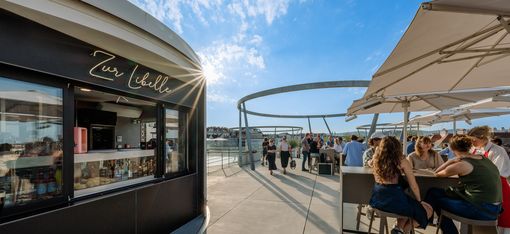 Bar Zur Libelle auf dem Dach des Leopold Museum im MuseumsQuartier Wien mit Gästen an Tischen unter Sonnenschirmen.