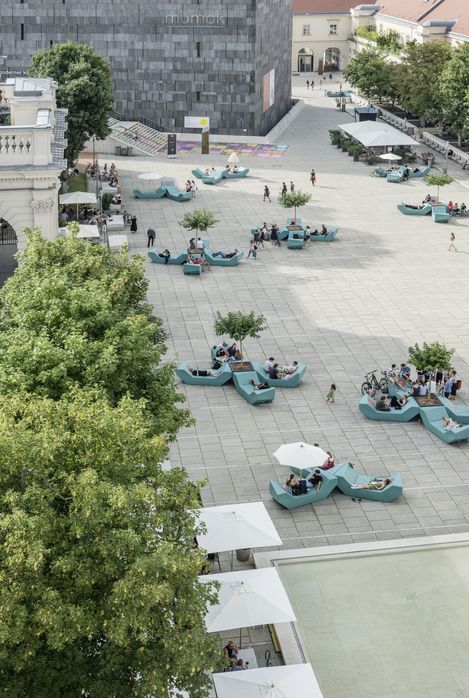 Overhead view of the main courtyard of MuseumsQuartier Vienna with numerous turquoise Enzi seating elements used by visitors to sit and lounge.