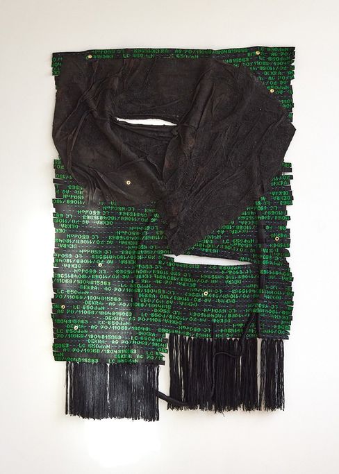 Textilkunstwerk mit schwarzem, zerknittertem Stoff auf grünem Hintergrund mit weißen Zahlen und schwarzen Fransen am unteren Rand
