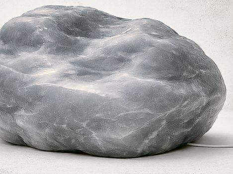 Großer, unregelmäßig geformter Stein mit glatter Oberfläche auf hellem Untergrund.