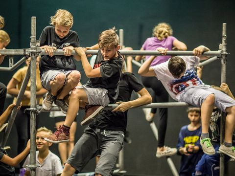 Children are climbing acrobatically on a scaffold made of iron poles.