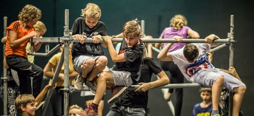 Children are climbing acrobatically on a scaffold made of iron poles.