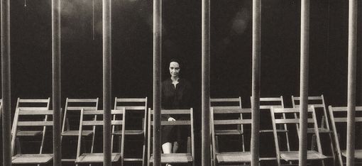 Eine Mannequin Puppe sitzt hinter Gittern auf einem Sessel.