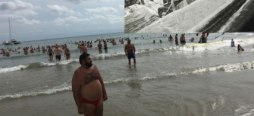 Männer, die am Strand und im Wasser stehen.