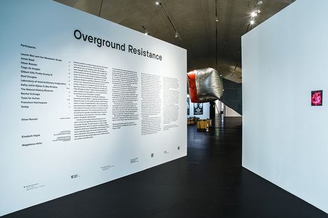 Large white wall with exhibition text and title lettering 'Overground Resistance' in a modern museum space.