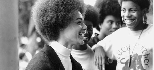 Vier Personen mit Afrofrisuren stehen nah beieinander, zwei tragen T-Shirts mit dem Schriftzug 'Black Panther Party' und einem Panther-Logo