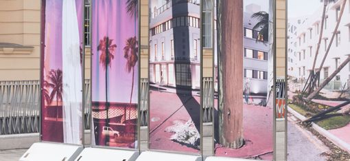Several upright rectangular panels displaying photographs of palm trees and flooded urban streets
