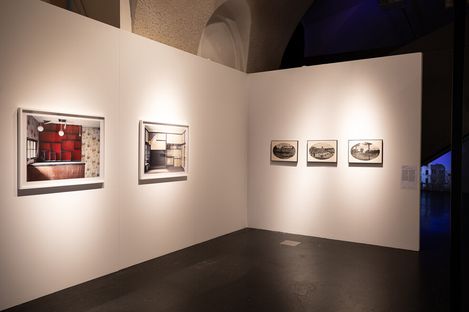 White exhibition wall with two framed photographs on the left and three smaller framed pictures on the right
