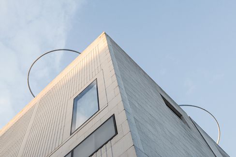 Gebäudeecke mit rechteckigen Fenstern und zwei großen Metallringen auf dem Dach