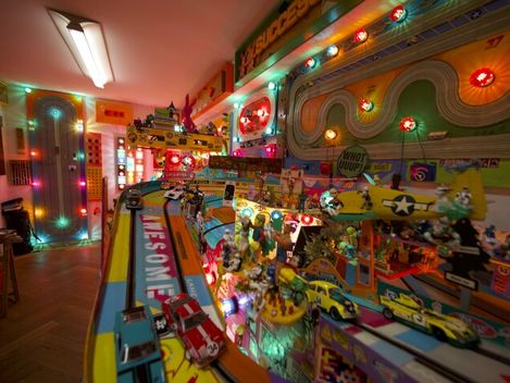 Colorfully lit toy race track with model cars in a room.
