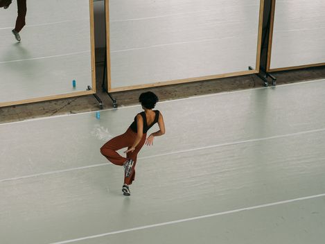 Eine Frau tanzt in einer Turnhalle vor einem Spiegel.