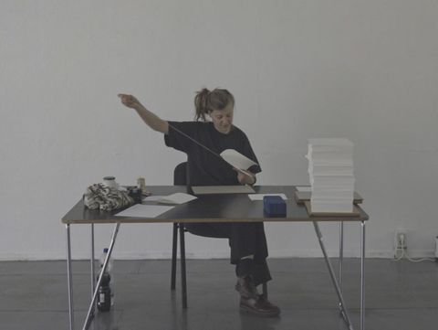 Person sitting at a table holding a thread stretched in front of them.