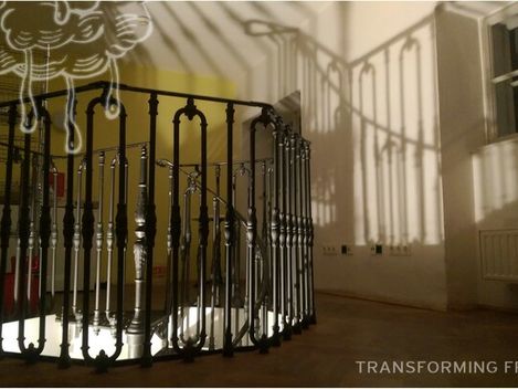 Schattenspiel von Treppengeländer und Fensterrahmen an einer Wand in einem leeren Raum mit Heizkörper