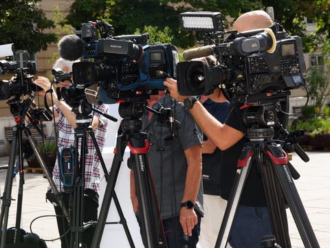 Mehrere Kamerateams mit professionellen Videokameras auf Stativen in einem Außenbereich.