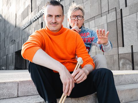 Die Künstler Oliver Hangl und Clemens Bacher sitzen auf der mumok Stiege.