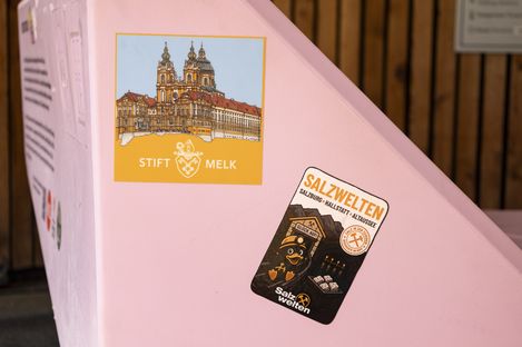 A person attaches a travel sticker to a pink Enzi at the Schafberg mountain station.
