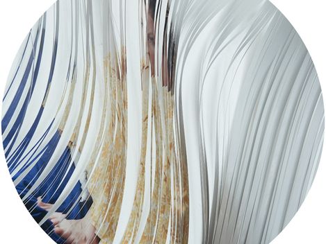 Person behind a wavy transparent surface with visible face and hands
