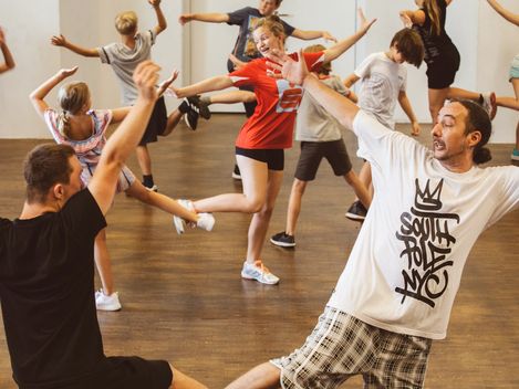Junge Menschen tanzen miteinander. Die Bewegung ist choreografiert, das heißt, sie nehmen alle die gleiche Pose ein.
