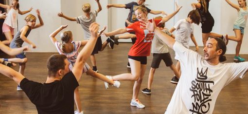 Young people are dancing together. The movements are choreographed, which means they are all striking the same pose.